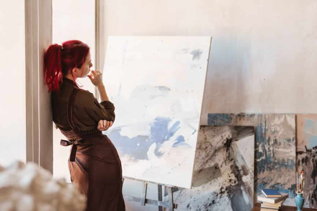 Young creative woman artist standing in front of a canvas in an art studio