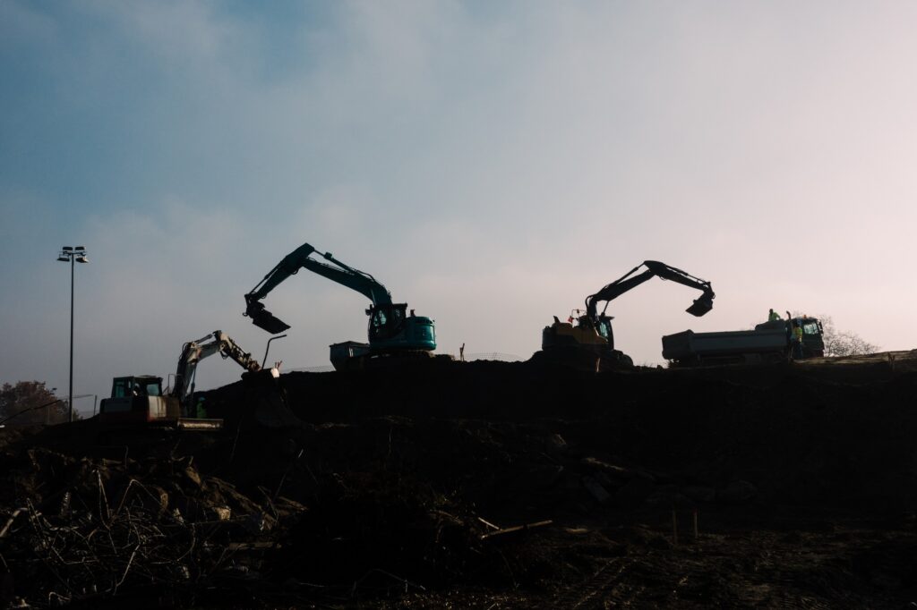 Diggers excavating land and freighting soil on trucks on blue sky background